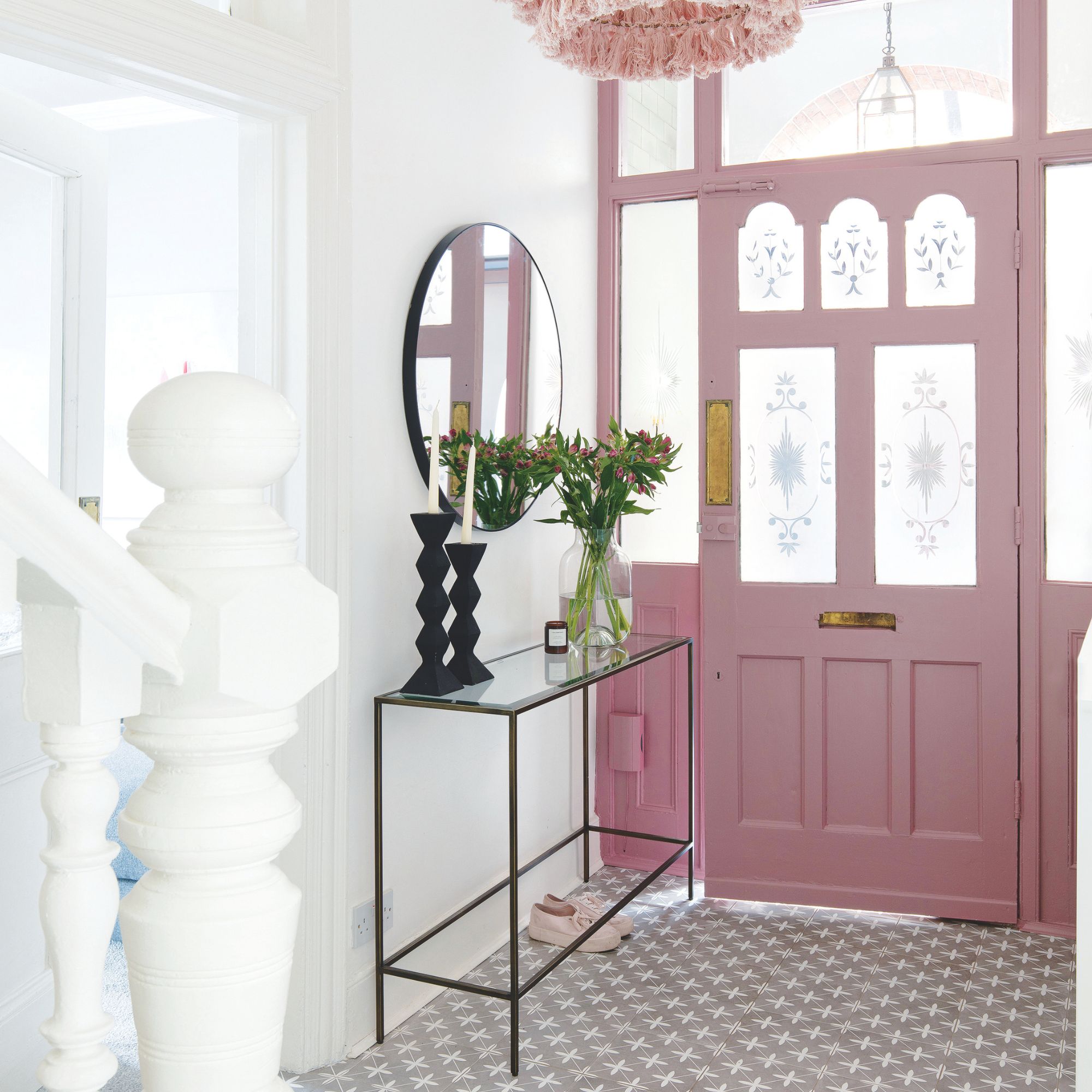 white painted hallway with grey patterned floor tiles and a pink painted front door