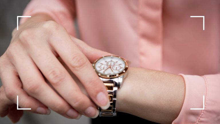 woman in a pink top looking at her watch