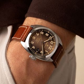 brown watch with leather strap, on man's wrist