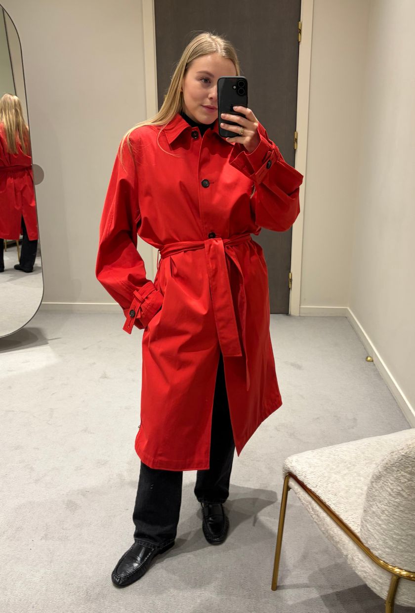 Woman wears red trench coat, black trousers and black loafers