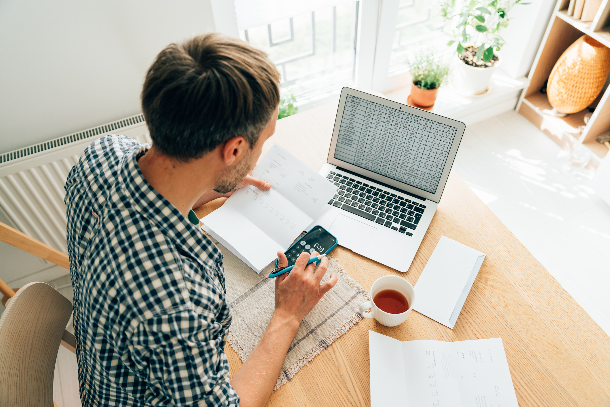Man using calculator and laptop computer to calculate tax