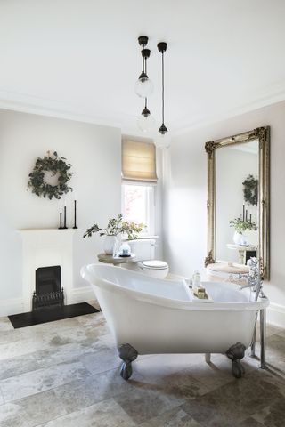bathroom with slipper bath white walls large mirror and small cast iron fireplace