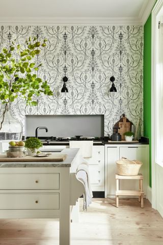 Green kitchen ideas featuring baroque style wallpaper and a bright green wall set against off white cabinetry and natural wooden flooring.