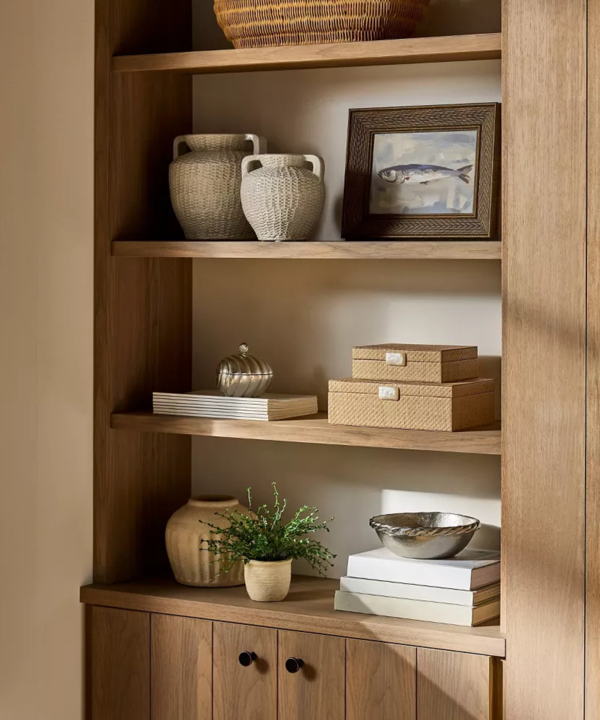a bookshelf decorated with books, boxes, plants, vases, and a picture frame