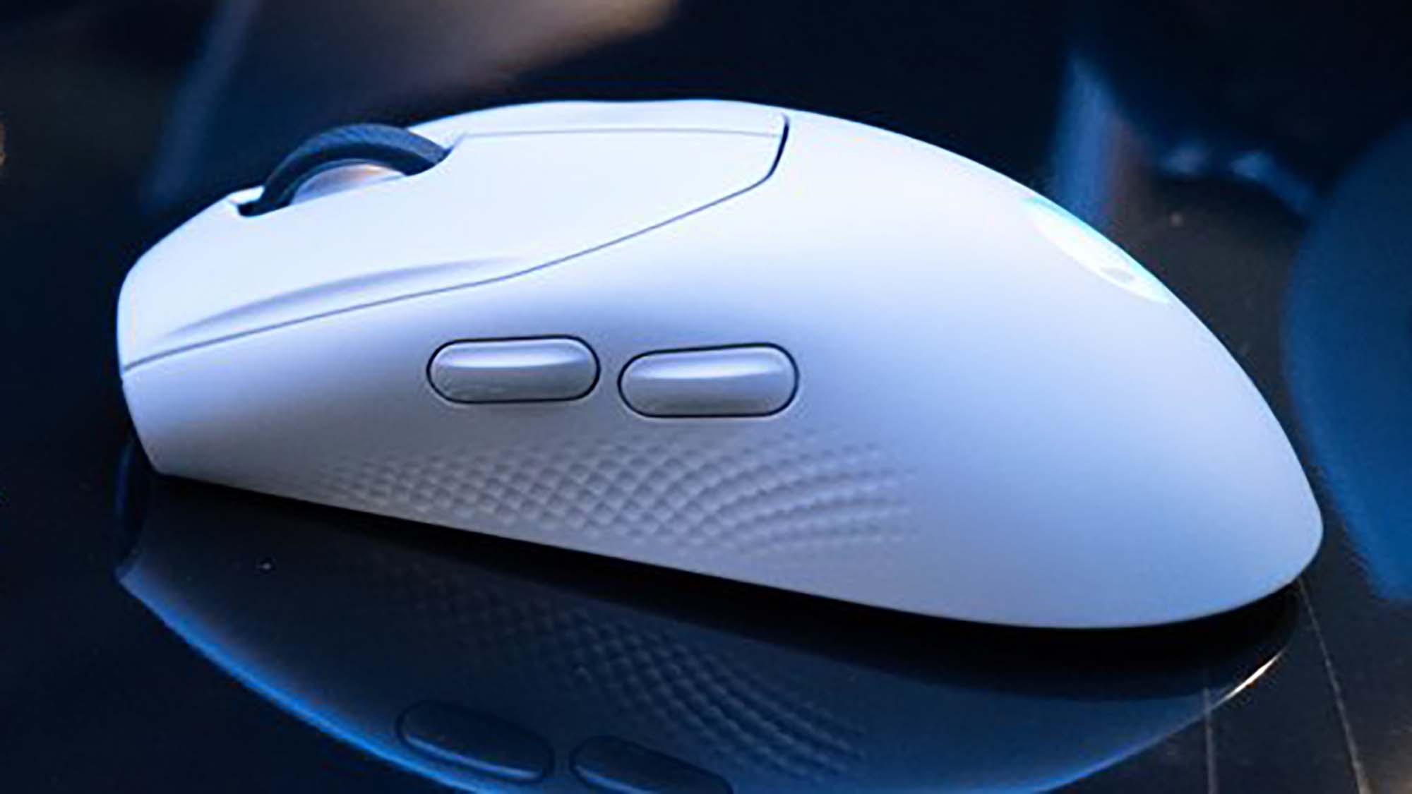 An Alienware Tri-Mode wireless gaming mouse on a reflective black surface in a darkened room