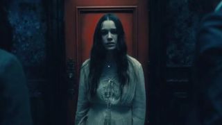 The ghost of a young woman standing in front of a red door during the Netflix horror series, The Haunting of Hill House.