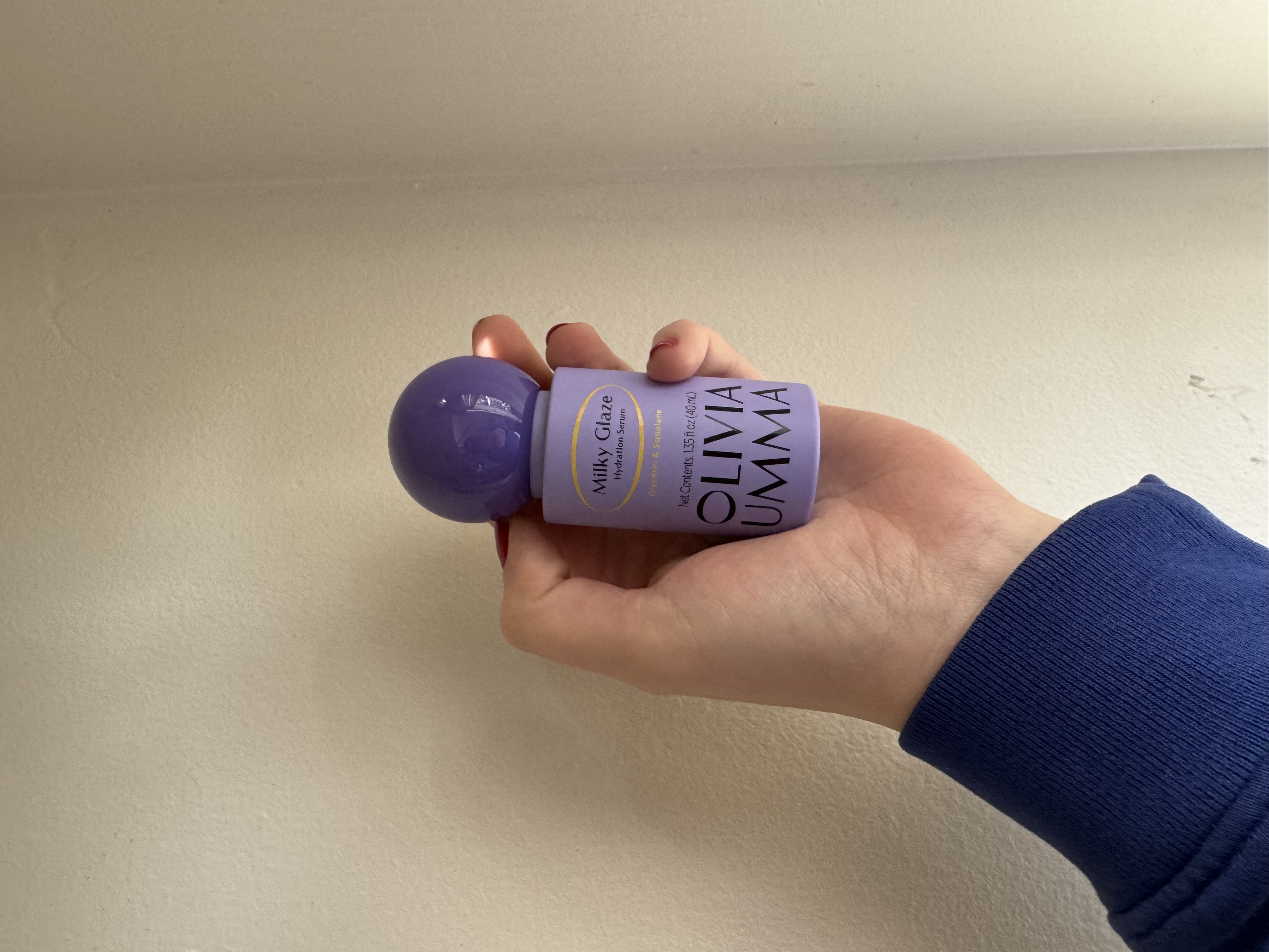 Sophia Vilensky holding a bottle of OLIVIAUMMA serum.