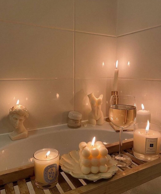 A bathtub and bath caddy filled with aesthetic vanilla candles