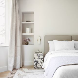 White bedroom with neutral headboard, marble table and built in shelving