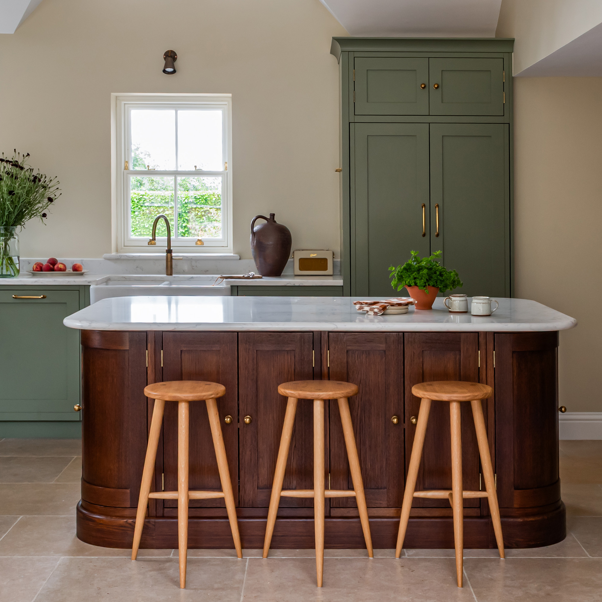 kitchen with cream wall green cabinetry and wooden curved kitchen island with stools