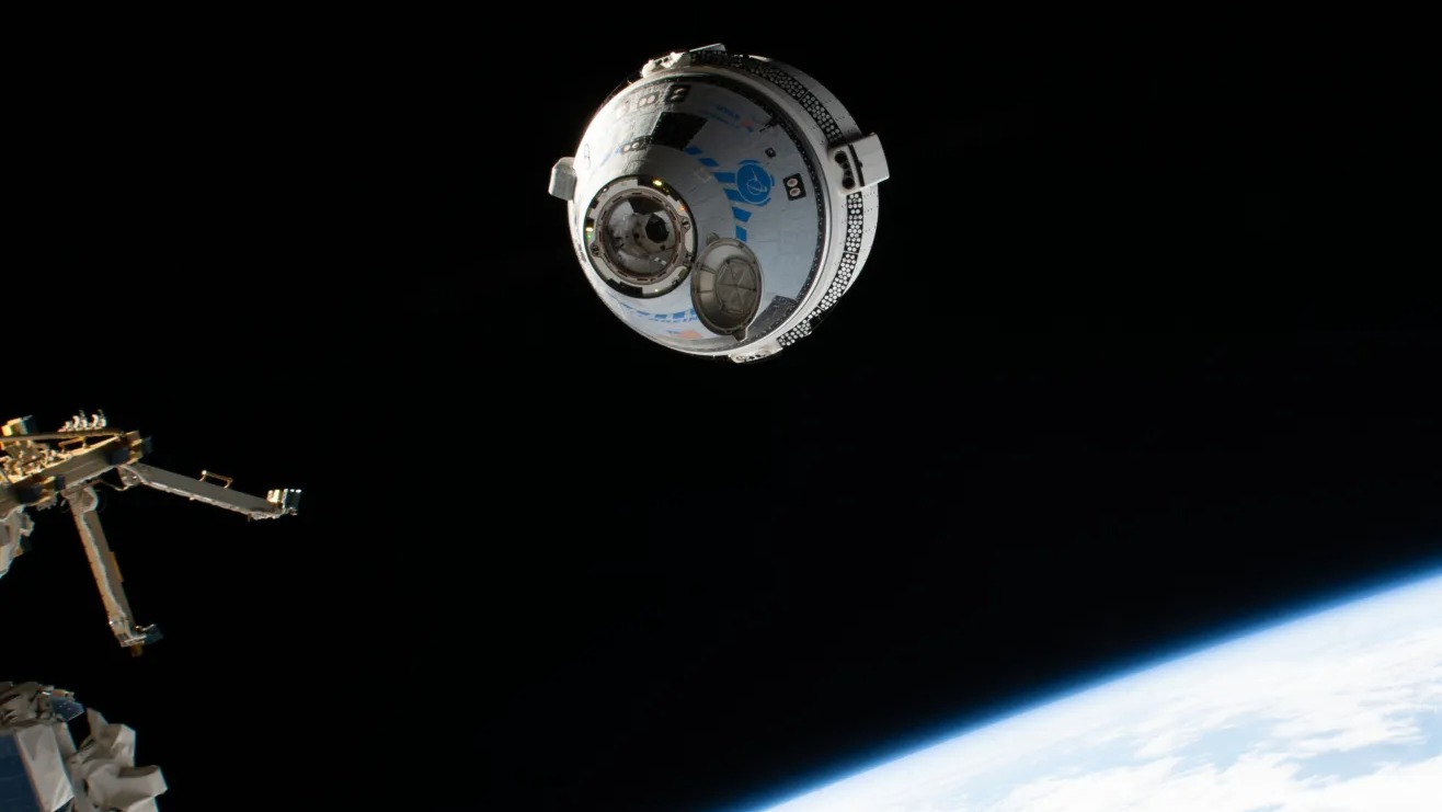 a grey-and-blue cone-shaped spacecraft floats above a sliver of earth as seen from space