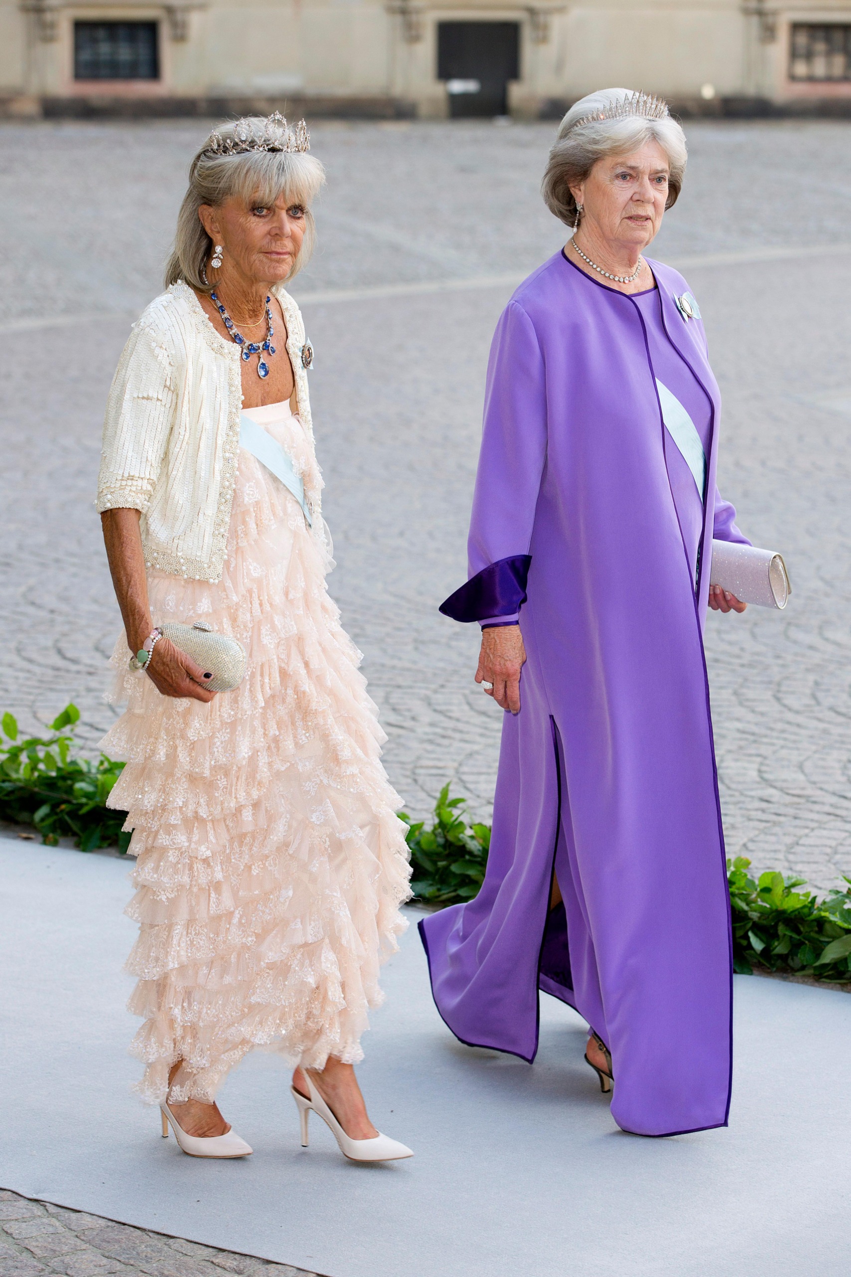 Princess Birgitta wearing a pink gown walking next to Princess Margretha in a purple dress
