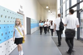 Girl walking down the school corridor next to group of other pupils