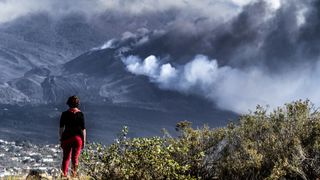 A hiker looks across the hill at a column of smoke