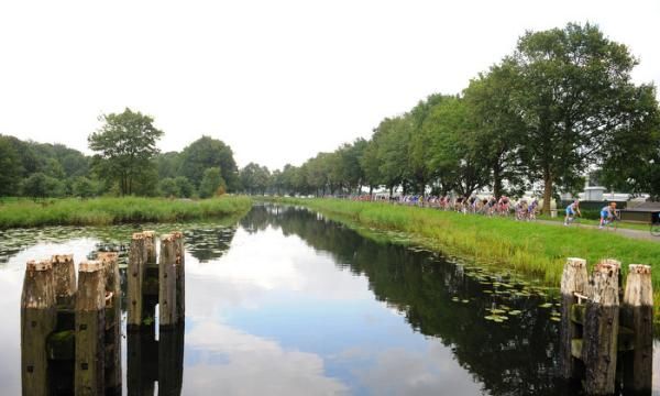 The peloton passes along one of the many canals in the region.