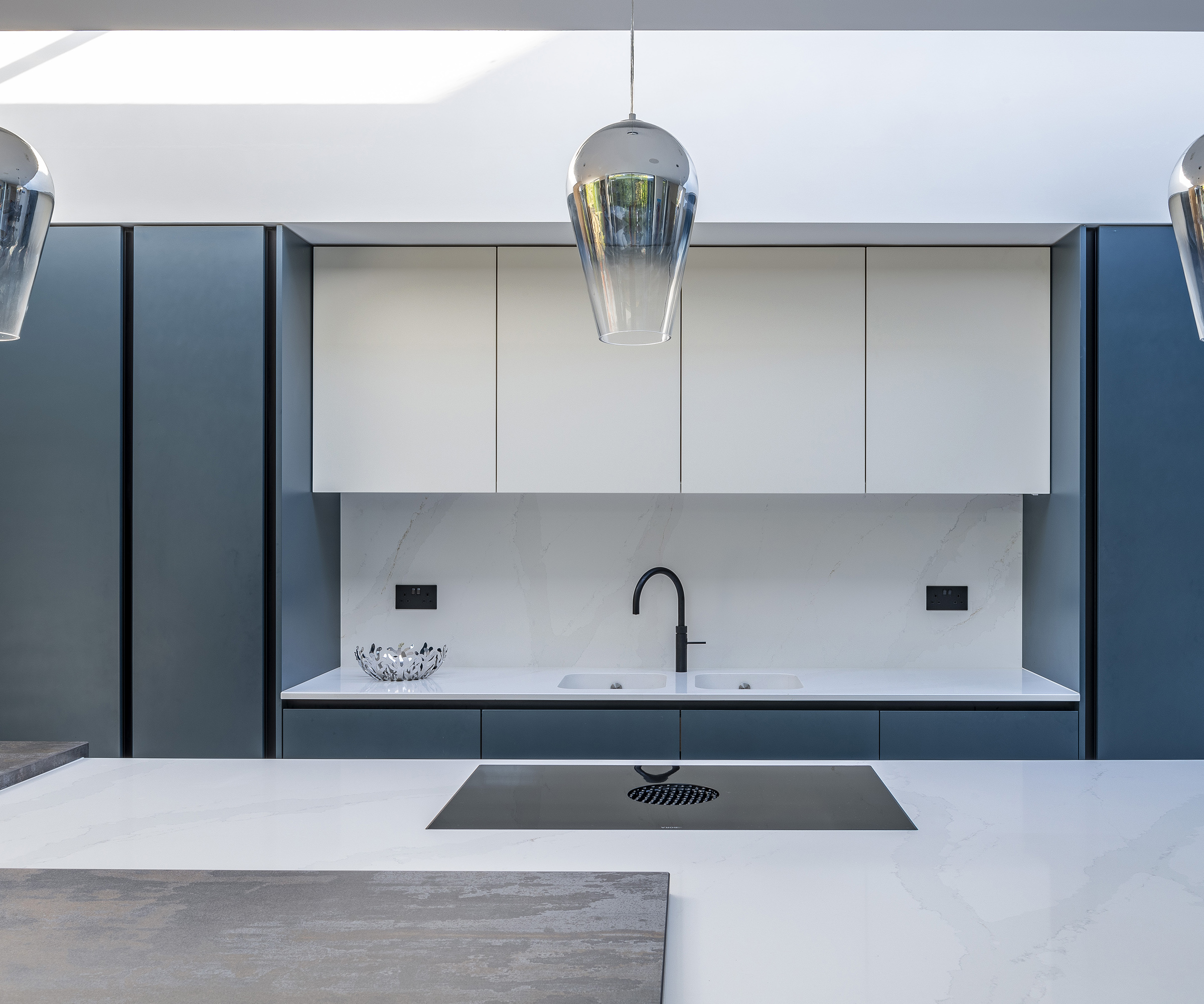 A modern kitchen with teal and white cabinets with sleek island