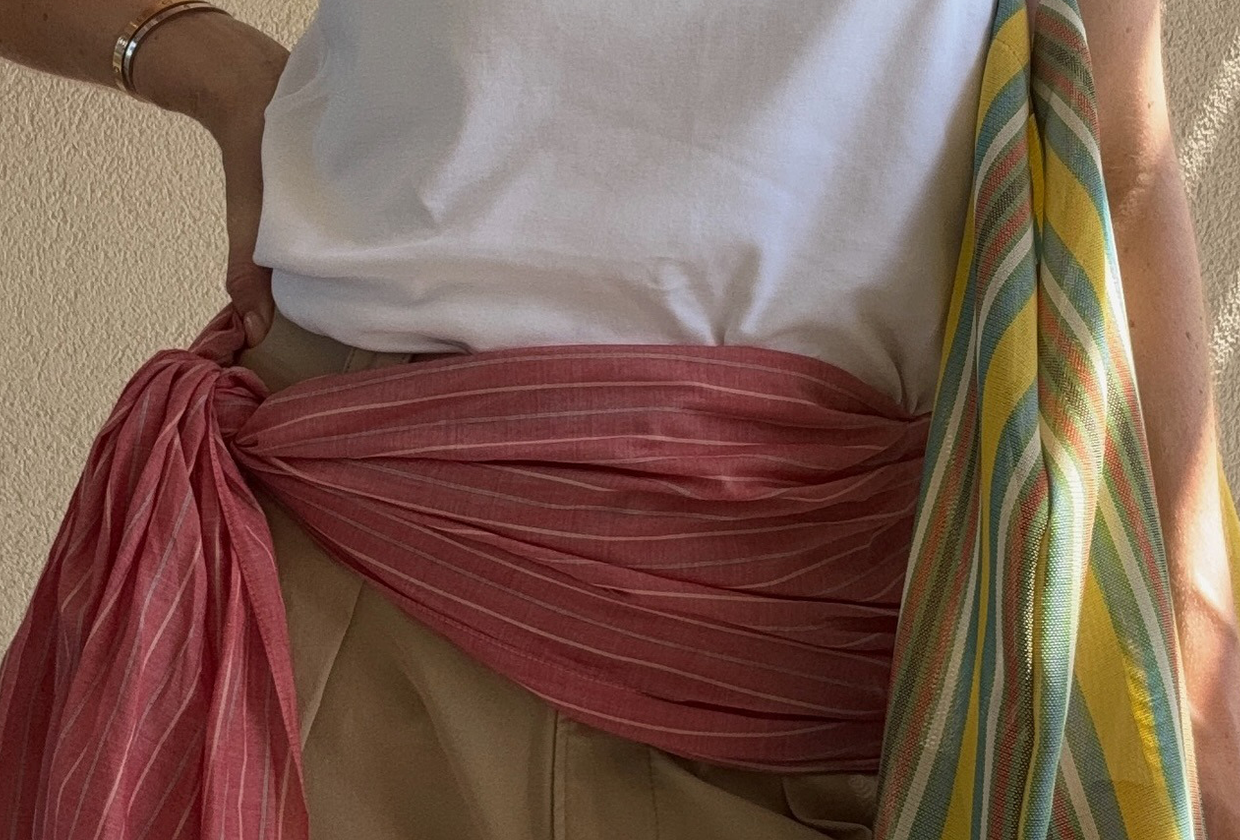 Woman wearing The Row striped Barn Tote with white t-shirt, khaki shorts, and red scarf around waist.