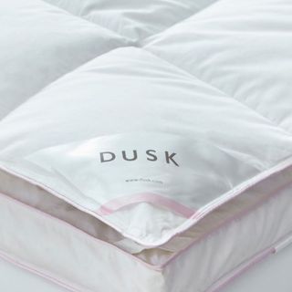 Corner of fdusk mattress topper with logo and pink piping