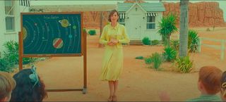 A still from "Asteroid City" showing Maya Hawke teaching a group of children about the solar system.