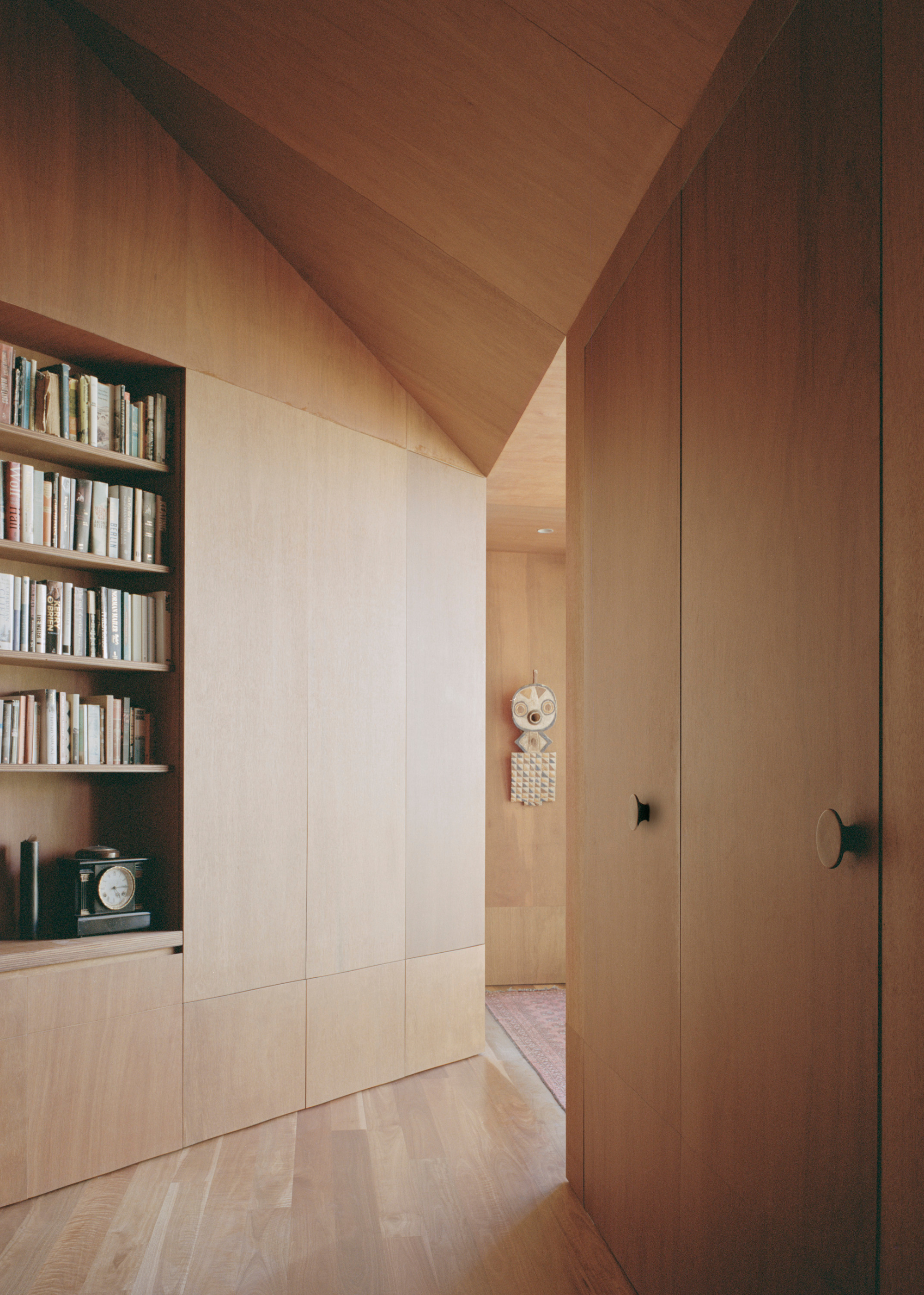 A wooden wardrobe in a bedroom with a bookshelf