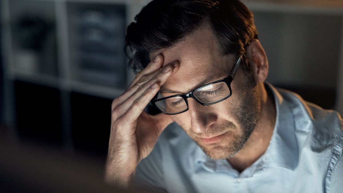 A male office worker experiencing a stress headache