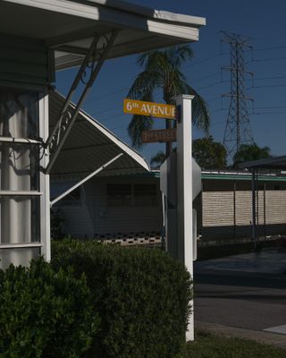 Orange street sign by house with 6th Avenue on it