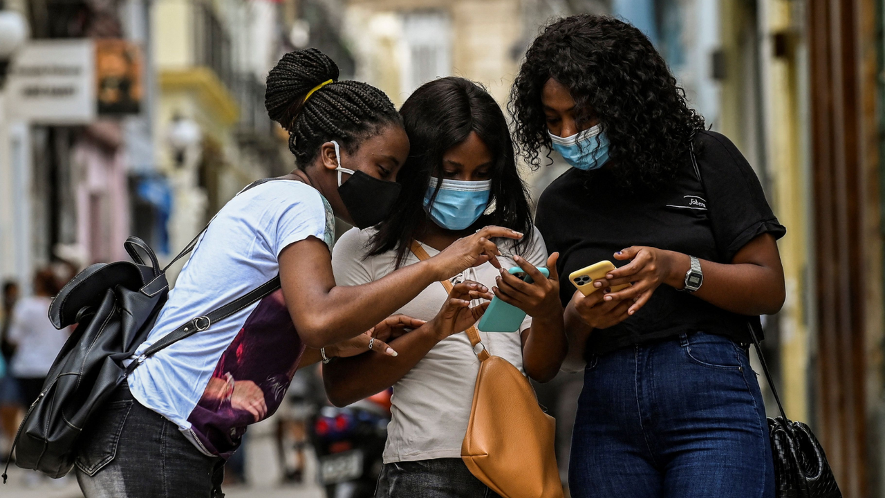 Women look at one another’s phones