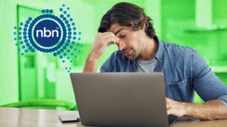 Anxious looking man sitting in front of a laptop at a table. The NBN Co logo is in the top left.