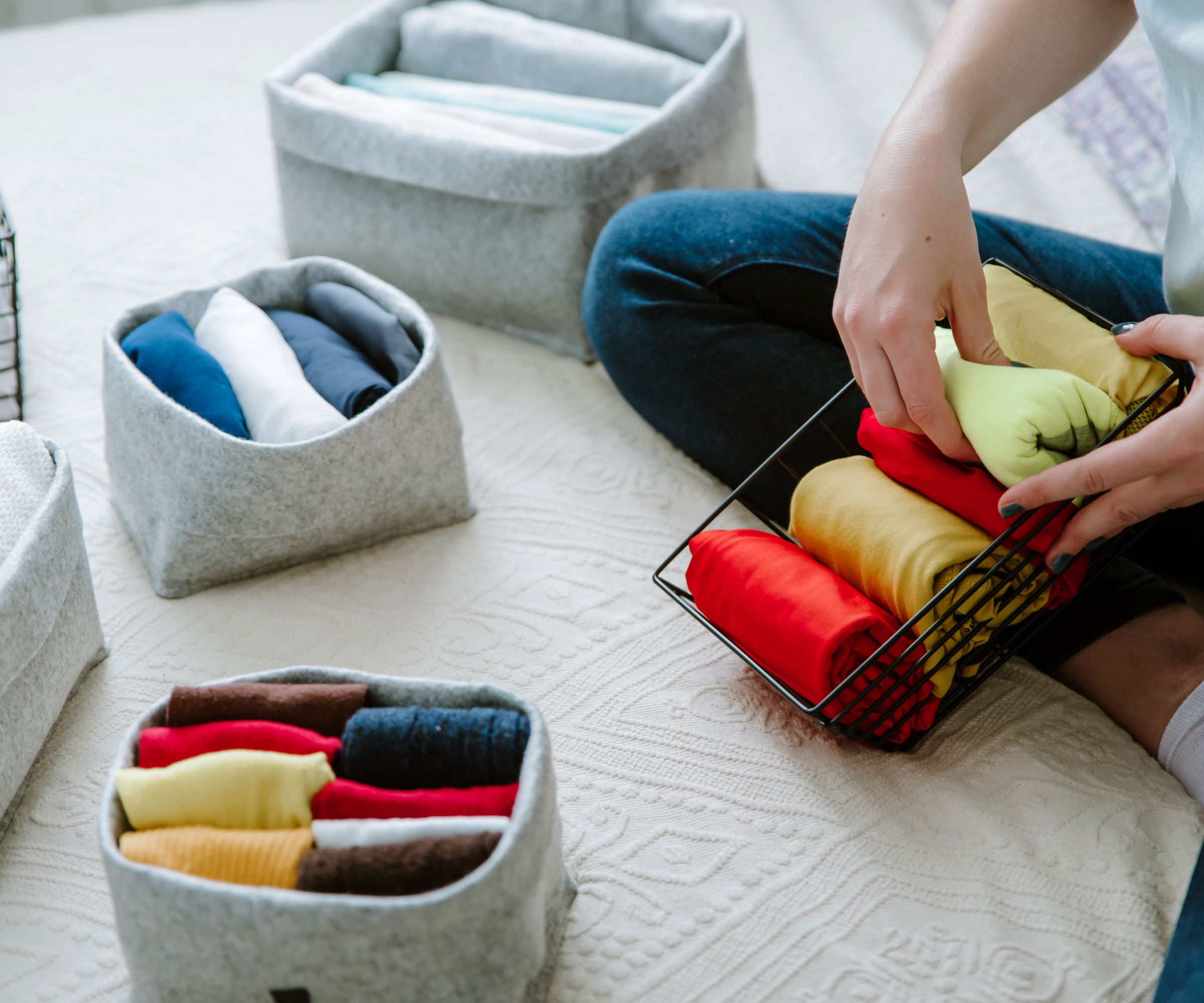 Person's hand organising clothes into a wired box surrounded by other clothing boxes