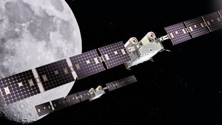two small rectangular spacecraft with long wing-like solar panels fly above the moon