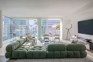 An open plan living room with a sage green sofa and large floor to ceiling windows