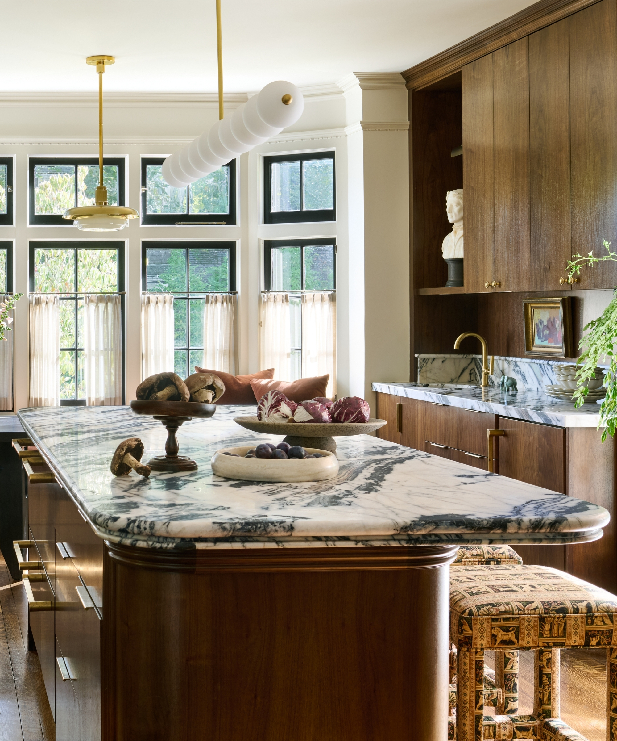 A kitchen with dark wood cabinets, white walls, marble countertops, and an decorative edge on the island counters