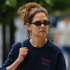 Katie Holmes carries a black Khaite bag and wears a navy sweatshirt featuring the words Happy hours