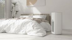 One of the best air purifiers standing next to a bed