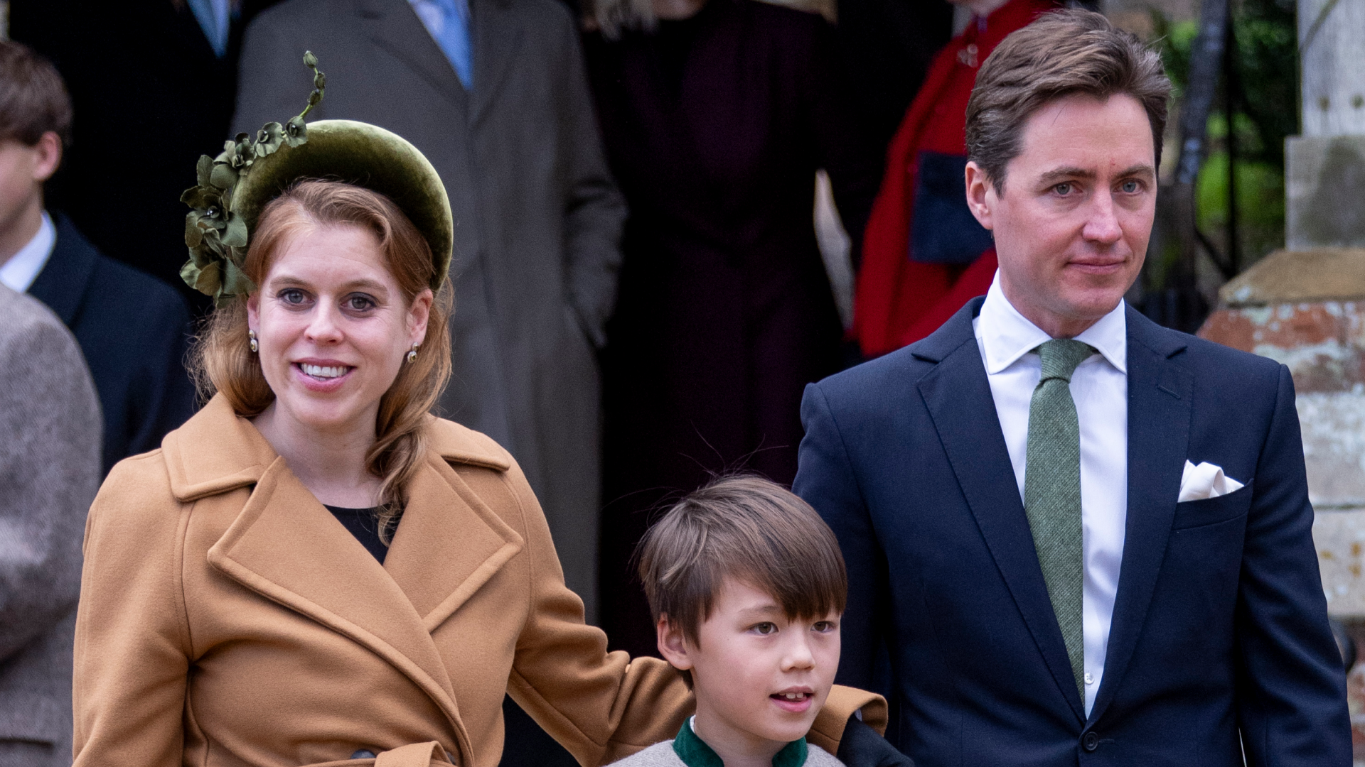 Princess Beatrice wearing a tan coat standing with her arm around her stepson, standing next to Edoardo Mapelli Mozzi