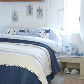 bedroom with white wall white window and bed with blue and white designed cushions