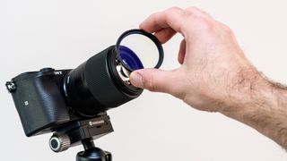 A hand adding a UV filter to a camera lens