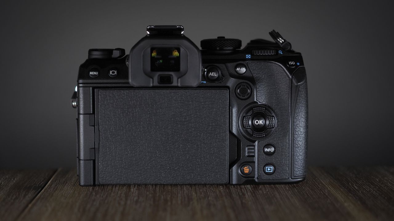 OM System OM-1 Mark II on a wooden surface, against a dark background