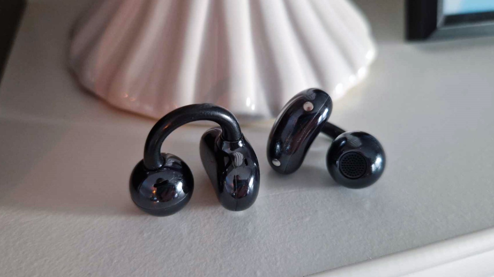 Huawei FreeClip-earbuds ligger bredvid varandra på ett vitt hyllplan.