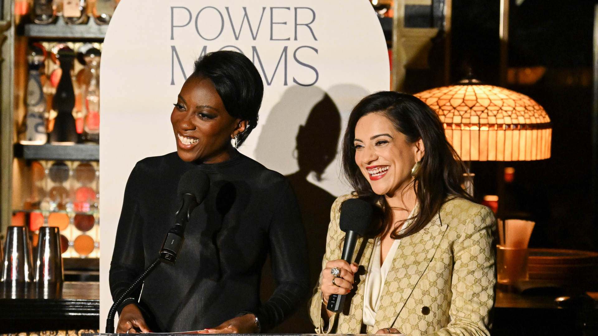 Nikki Ogunnaike and Reshma Saujani speak at a podium.