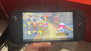Hand holding Nintendo Switch 2 console playing Mario Kart World