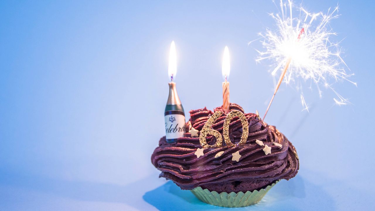 Sparklers and a &amp;quot;60&amp;quot; candle adorn a chocolate cupcake.