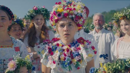 Dani looks shocked as she stands next to some other women in A24 folk horror movie Midsommar