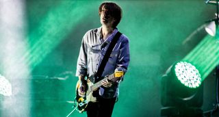 Steven Wilson performs live onstage with his custom shop Fender Telecaster. The stage is illuminated in green stage lights.
