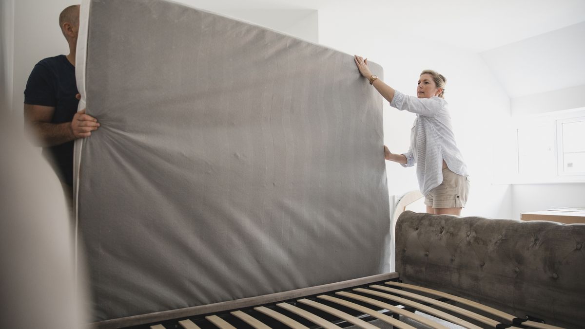 A couple rotate their mattress before putting it back on a slatted bed base