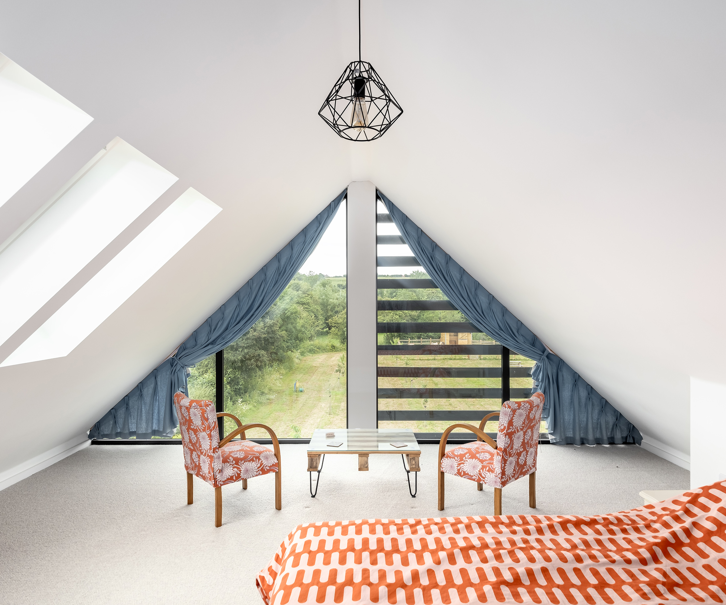 A pitched roof loft bedroom in a self build home with large glazing