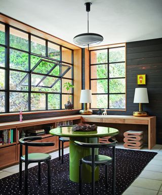 library with green table black chairs, black patterned rug and wooden built in cabinet