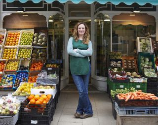 female greengrocer outside her shop