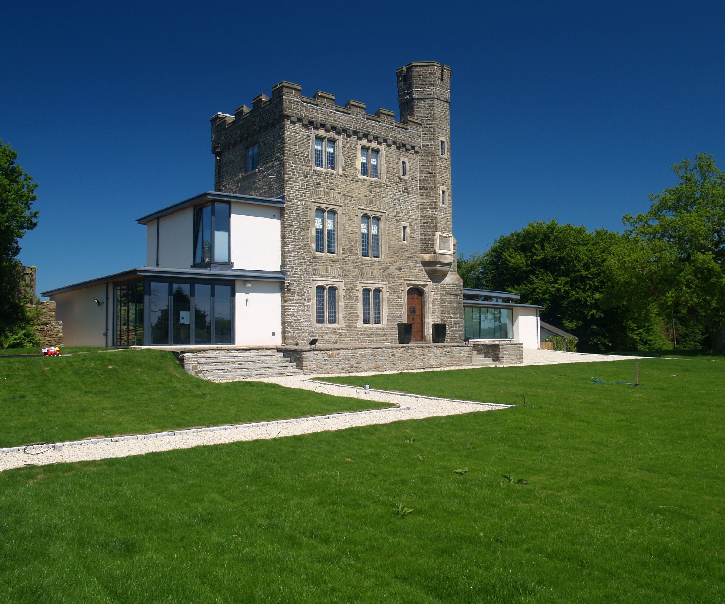 A stone folly with contemporary render and glass extension wings