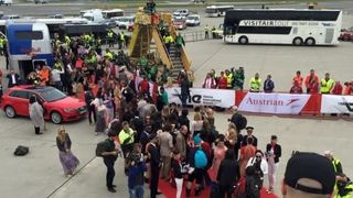 Press taking pictures of people de-boarding a plane on a red carpet